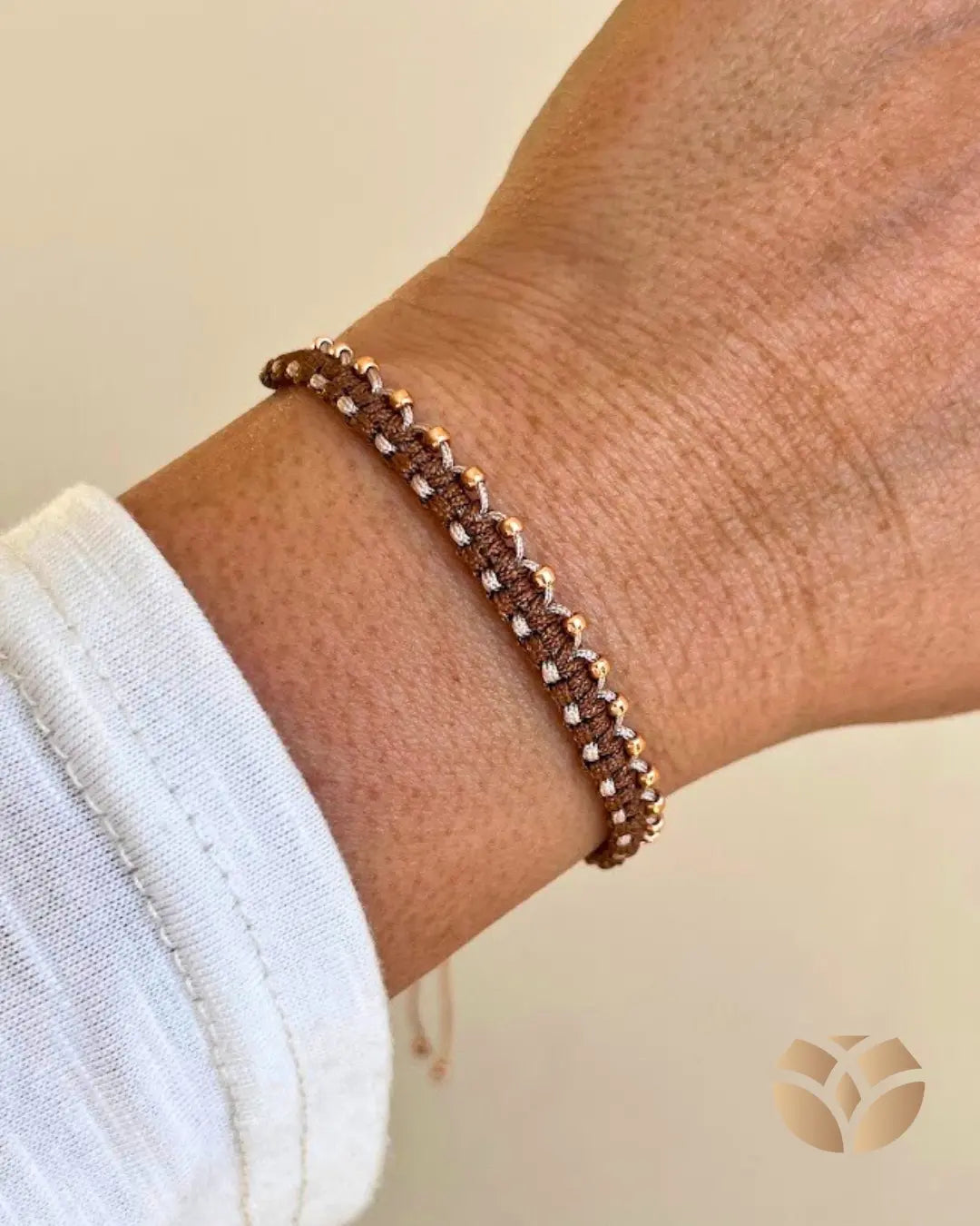Pulsera tejida con técnica macramé, combina nudo plano con nudo alondra, en tonos café y beige, lleva a un lado mostacillas doradas para resaltar la belleza del tejido. Es ajustable a cualquier muñeca.