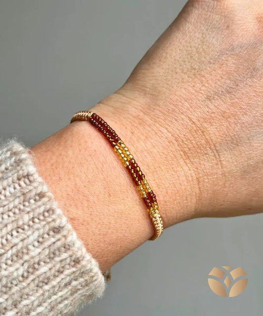 La Pulsera Pipa está hecha a mano en tejido macramé con nudo plano, incorporando delicadas mostacillas en tonos dorados y marrones que aportan brillo y calidez a tu estilo.