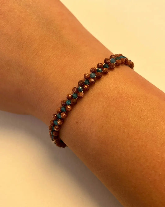 Pulsera tejida que lleva dos piedras, Apatita color azul con toques claros y piedra del sol color bronce con puntos brillantes.
